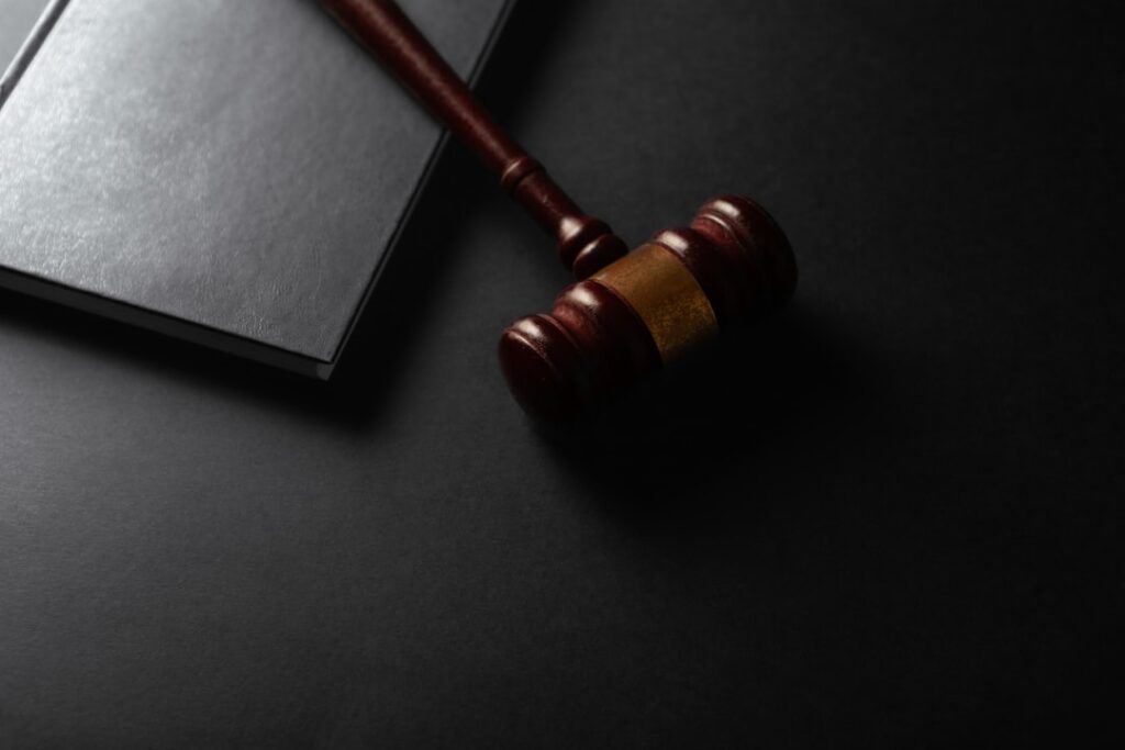 A wooden gavel resting on a dark surface next to a closed notebook