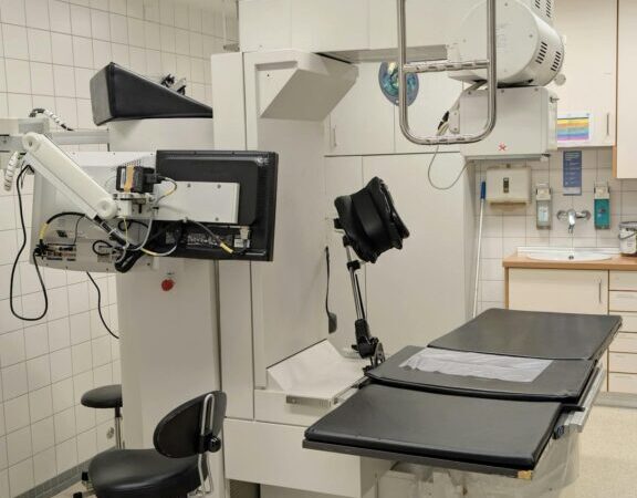 Medical imaging equipment in a clinical setting, featuring a treatment table and advanced imaging technology.