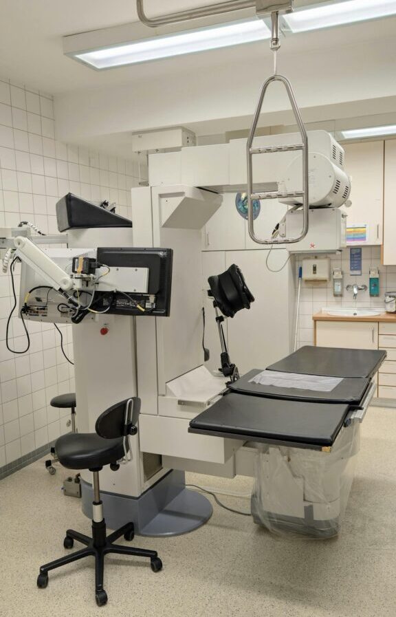 Medical imaging equipment in a clinical setting, featuring a treatment table and advanced imaging technology.