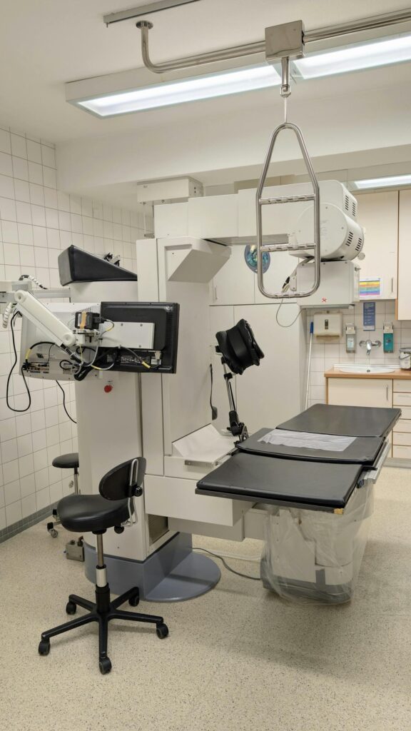 Medical imaging equipment in a clinical setting, featuring a treatment table and advanced imaging technology.